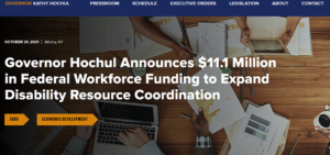 A conference room table with a laptop, tablet, chart, and paperwork and the text: "Governor Hochul Announces $11.1 Million in Federal Workforce Funding to Expand Disability Resource Coordination."