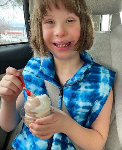 Kenley smiling and enjoying ice scream while seated in a car