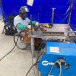 Larry Phillips, a black man who uses a wheelchair, working with welding tools while at work