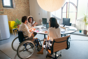 Three colleagues, one of whom is a wheelchair user, sit in an office together.